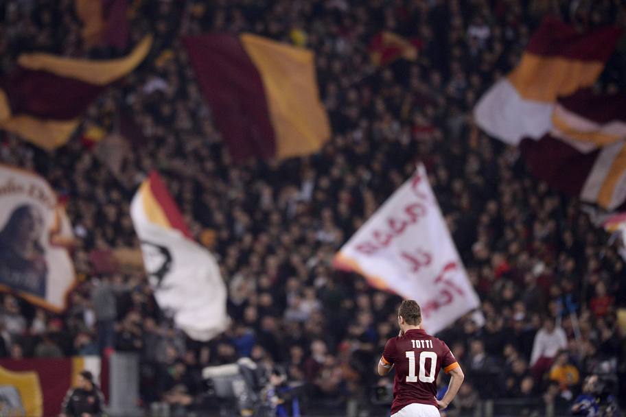 Francesco Totti si prende una pausa: dietro di lui lo sfondo di bandiere della Roma. LaPresse